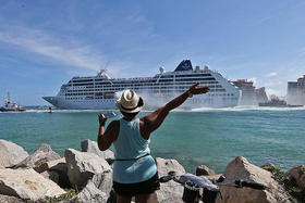 Una mujer saluda a los pasajeros del crucero Adonia a su salida del puerto de Miami en ruta hacia Cuba en mayo del 2016